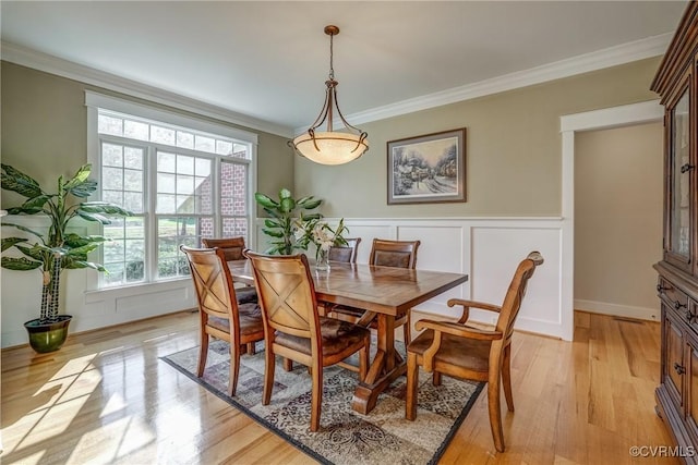 dining area with crown molding and light hardwood / wood-style floors