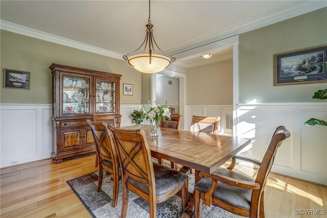 dining space featuring light wood-type flooring and ornamental molding