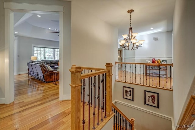 stairway featuring hardwood / wood-style floors and an inviting chandelier