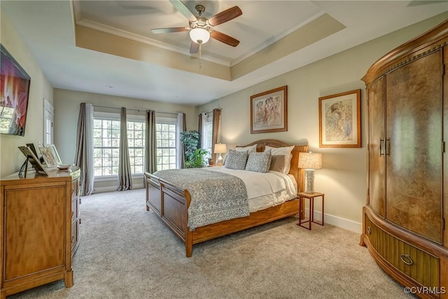 carpeted bedroom with a raised ceiling, ceiling fan, and ornamental molding