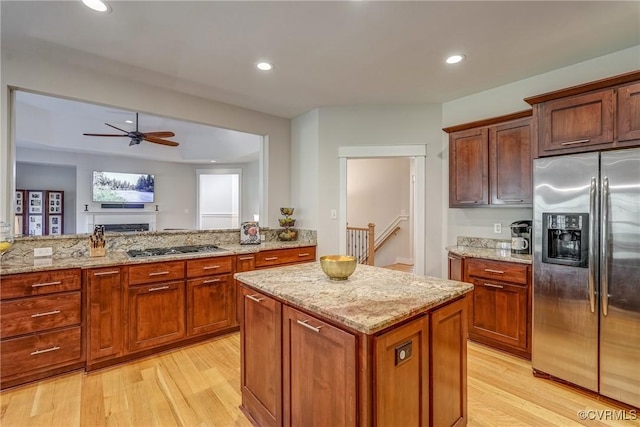 kitchen with a center island, light wood-type flooring, light stone countertops, and stainless steel appliances