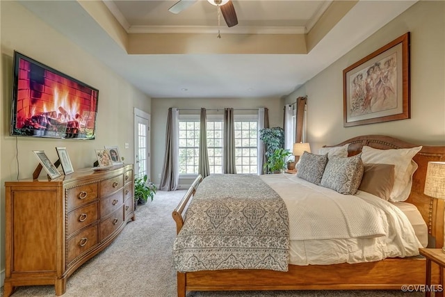 carpeted bedroom with a raised ceiling, ceiling fan, and ornamental molding