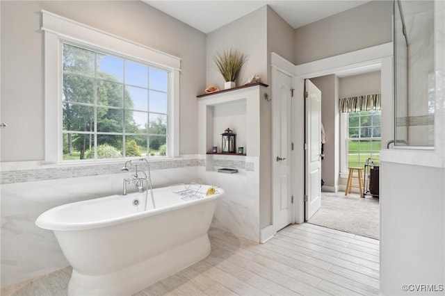 bathroom featuring hardwood / wood-style flooring, a washtub, and tile walls