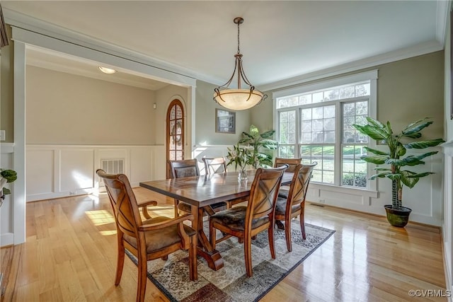 dining room with light wood-type flooring and ornamental molding