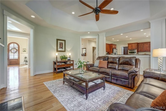 living room featuring light hardwood / wood-style floors, ceiling fan, and a tray ceiling