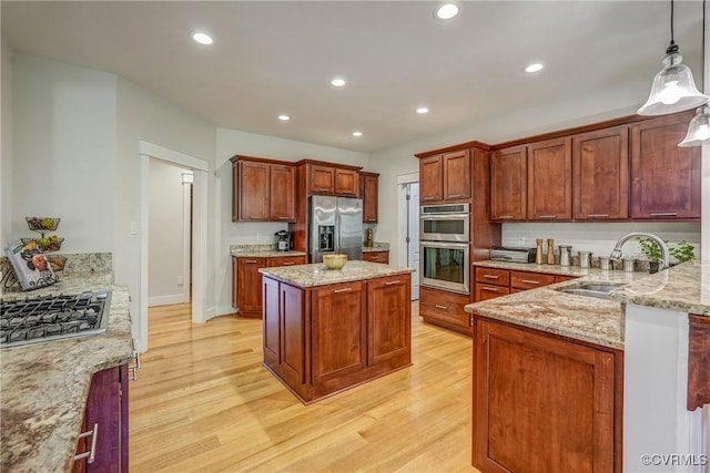 kitchen with sink, light stone counters, pendant lighting, appliances with stainless steel finishes, and light wood-type flooring