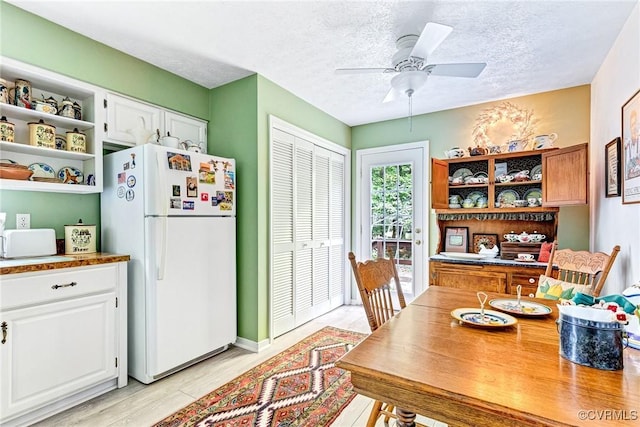 dining space featuring ceiling fan, light wood-type flooring, and a textured ceiling