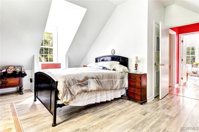 bedroom with multiple windows, vaulted ceiling, and light wood-type flooring