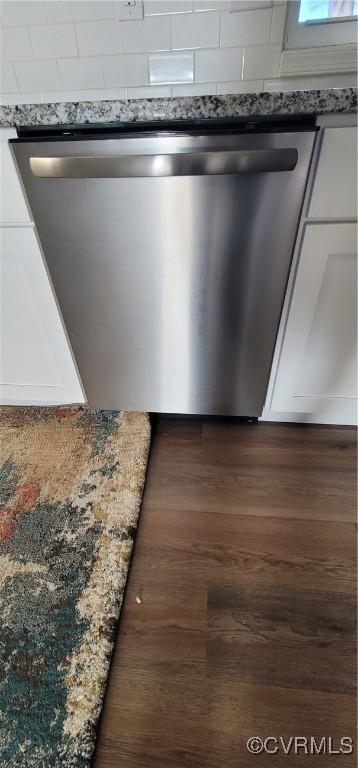 room details featuring stainless steel dishwasher, white cabinetry, and dark wood-type flooring