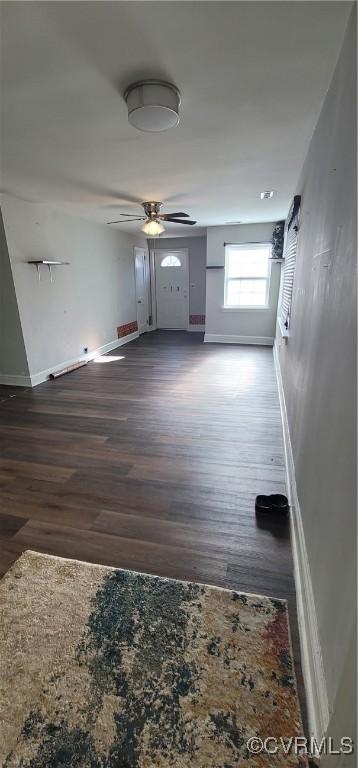 unfurnished living room featuring ceiling fan and dark wood-type flooring