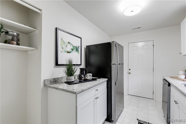 kitchen with appliances with stainless steel finishes, white cabinetry, and light stone counters