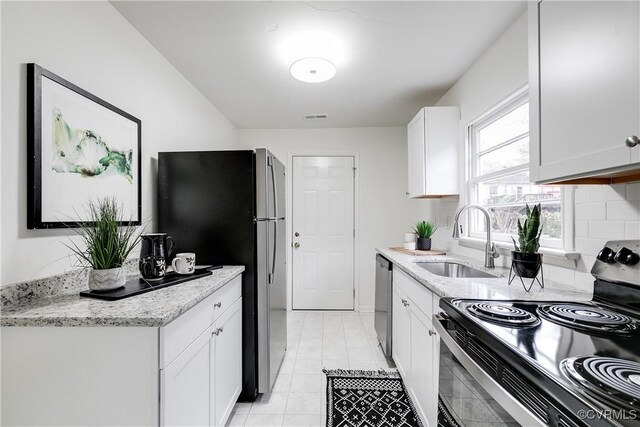 kitchen featuring white cabinetry, sink, light stone counters, and appliances with stainless steel finishes