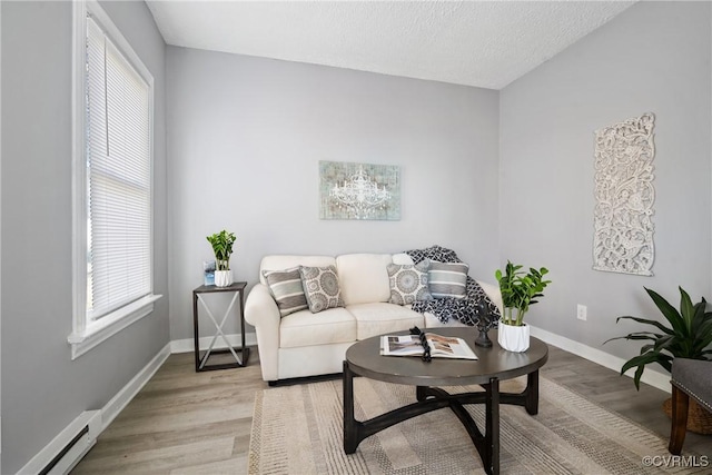 living room with a baseboard radiator, a textured ceiling, and light hardwood / wood-style floors