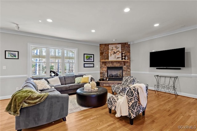 living room with light hardwood / wood-style floors, ornamental molding, and a fireplace