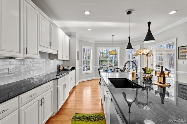 kitchen featuring white cabinets, decorative light fixtures, sink, and dark stone counters