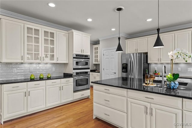 kitchen featuring light wood-type flooring, stainless steel appliances, crown molding, pendant lighting, and white cabinets