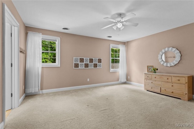 unfurnished bedroom featuring ceiling fan, light colored carpet, and multiple windows