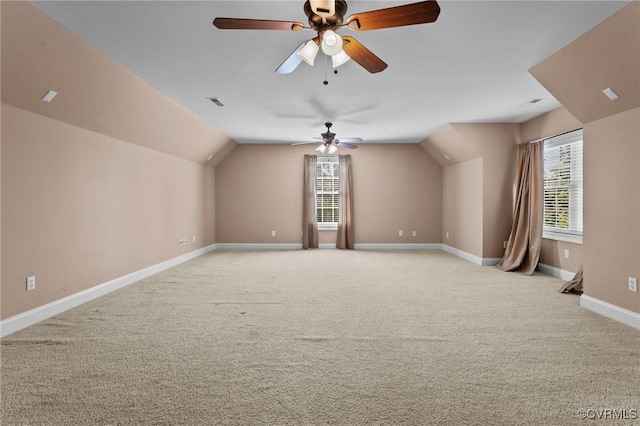 bonus room with ceiling fan, light colored carpet, a healthy amount of sunlight, and vaulted ceiling