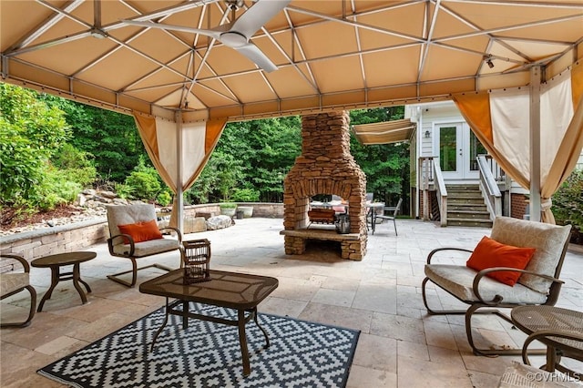 view of patio / terrace featuring an outdoor stone fireplace, ceiling fan, and a gazebo