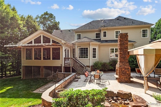 rear view of property with a lawn, a sunroom, and a patio