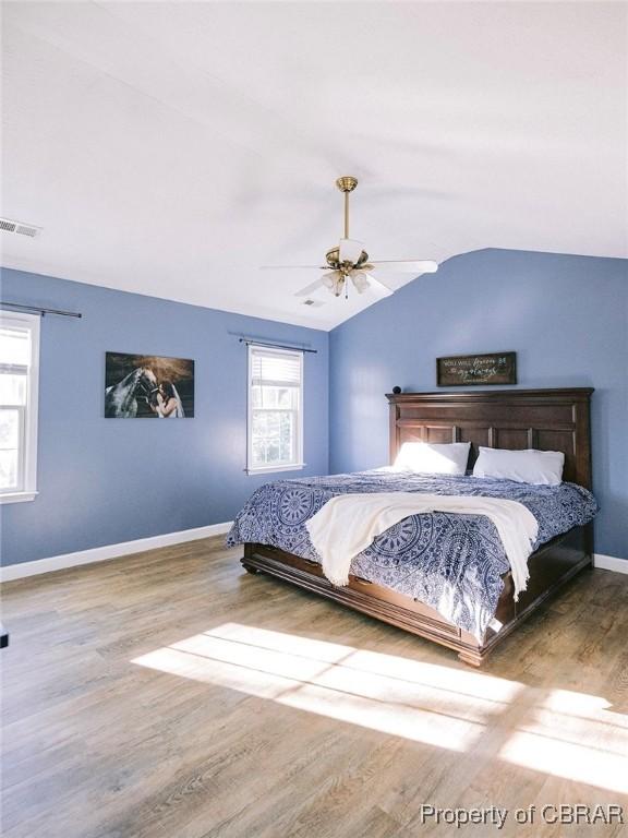 bedroom with ceiling fan, vaulted ceiling, and hardwood / wood-style flooring