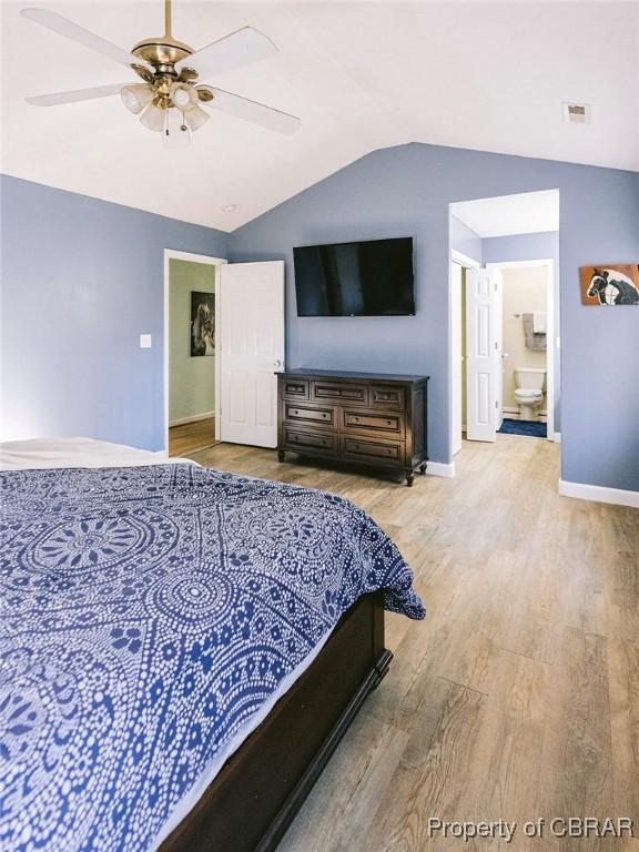 bedroom featuring ceiling fan, lofted ceiling, light hardwood / wood-style flooring, and ensuite bath