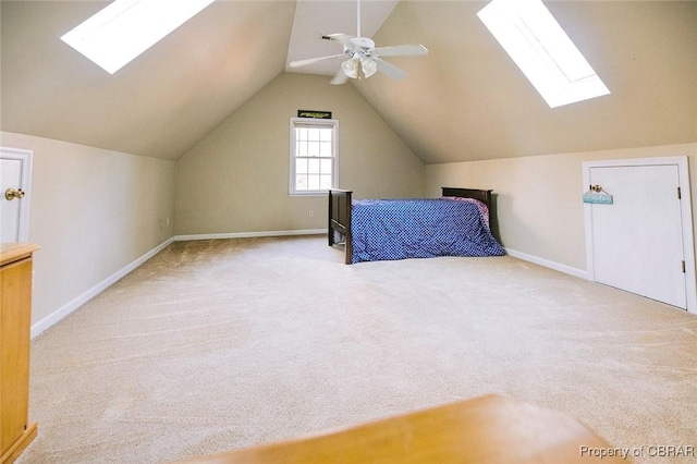 unfurnished bedroom featuring ceiling fan, vaulted ceiling with skylight, and light colored carpet