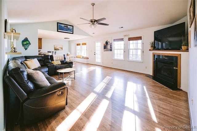 living room with ceiling fan, light wood-type flooring, and vaulted ceiling