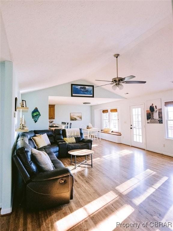 living room featuring ceiling fan, light hardwood / wood-style floors, and vaulted ceiling