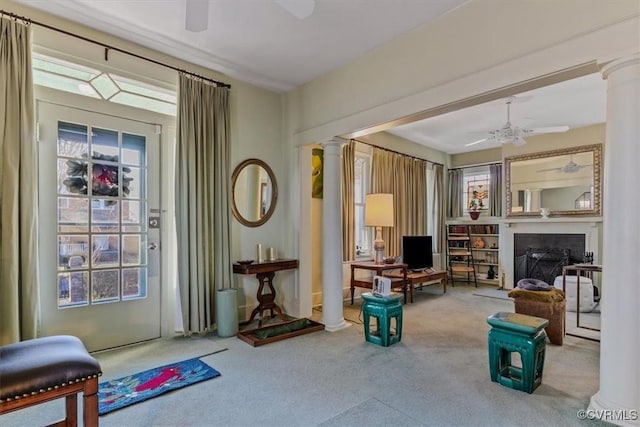 living area featuring ceiling fan, carpet floors, and decorative columns