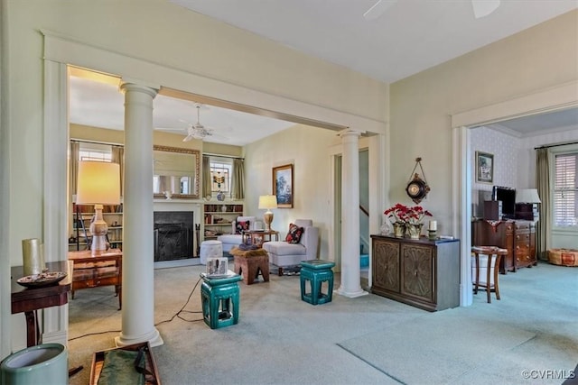 living room with ceiling fan, ornate columns, and light carpet