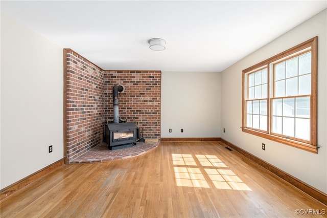 unfurnished living room with a wood stove and light hardwood / wood-style flooring