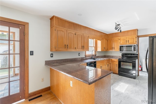 kitchen with black appliances, kitchen peninsula, sink, and a wealth of natural light