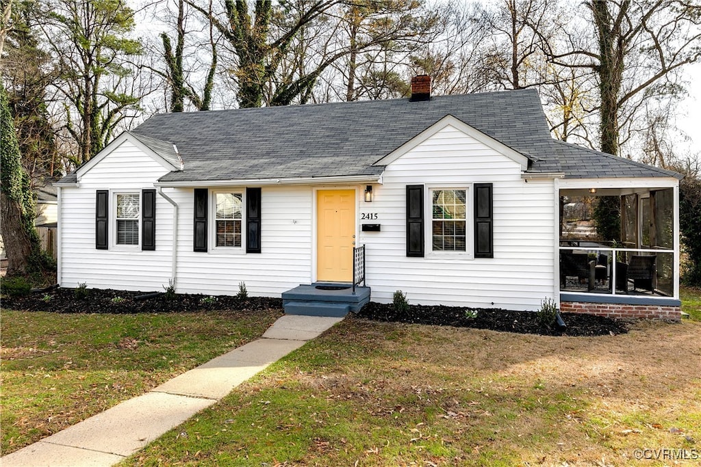 view of front of home featuring a front yard and a sunroom