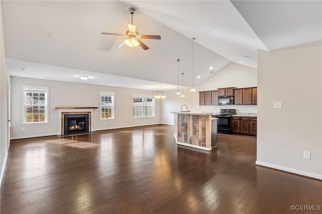 unfurnished living room featuring a healthy amount of sunlight, ceiling fan with notable chandelier, dark hardwood / wood-style floors, and high vaulted ceiling