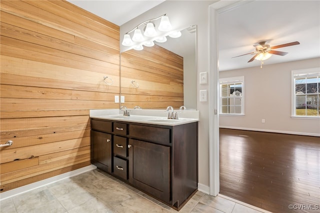 bathroom featuring ceiling fan, vanity, and wood walls