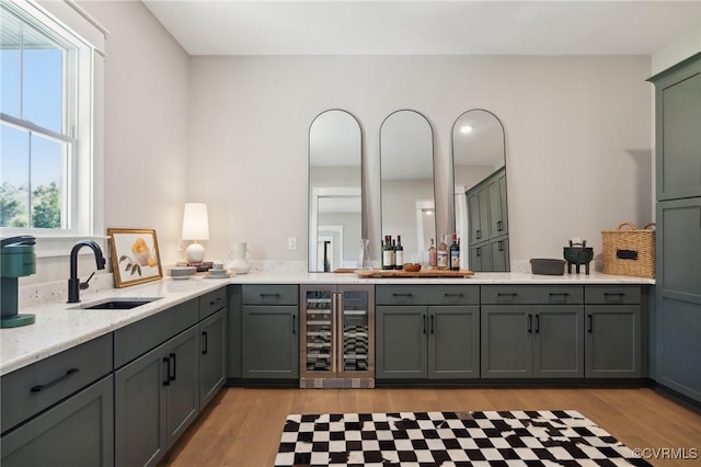 interior space with light hardwood / wood-style floors, light stone countertops, sink, and beverage cooler