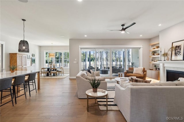 living room featuring dark hardwood / wood-style flooring, ceiling fan, built in features, and a baseboard radiator