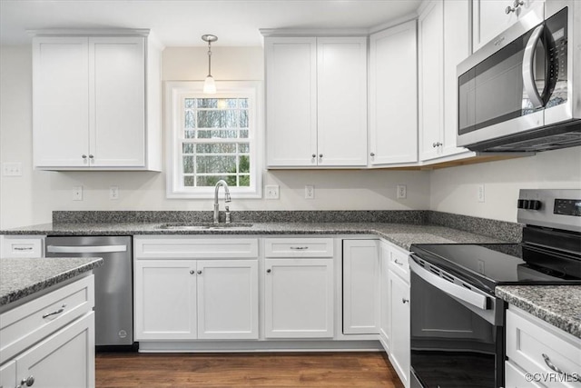 kitchen with appliances with stainless steel finishes, white cabinetry, hanging light fixtures, and sink