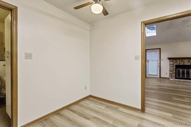 spare room with ceiling fan, light hardwood / wood-style floors, and a fireplace