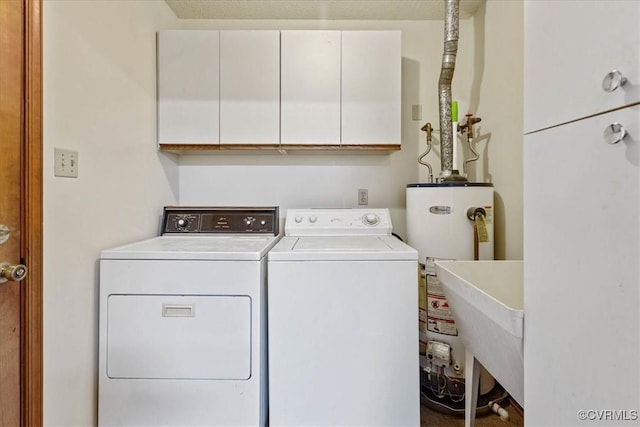 clothes washing area featuring cabinets, washer and clothes dryer, and water heater