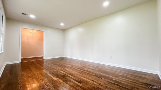 spare room with dark hardwood / wood-style flooring and a notable chandelier