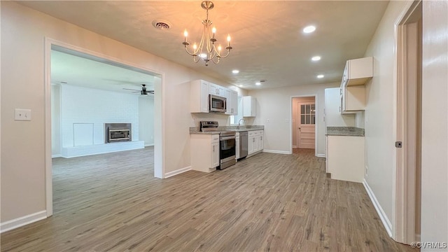 kitchen featuring pendant lighting, sink, light wood-type flooring, white cabinetry, and stainless steel appliances