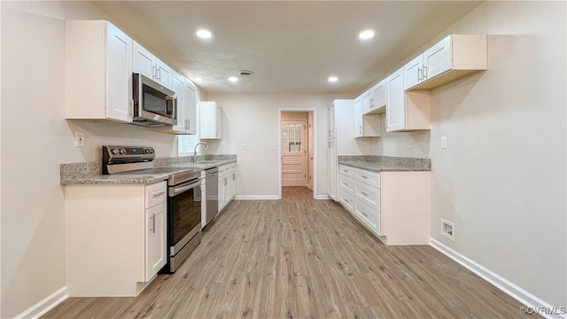 kitchen with white cabinets, sink, light hardwood / wood-style flooring, light stone counters, and stainless steel appliances