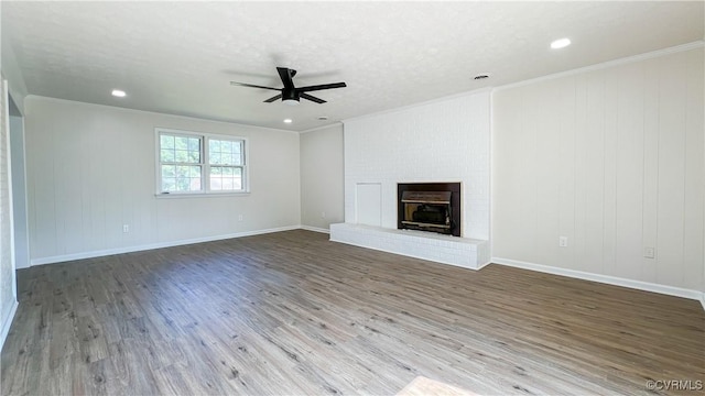 unfurnished living room featuring crown molding, ceiling fan, a fireplace, and dark wood-type flooring