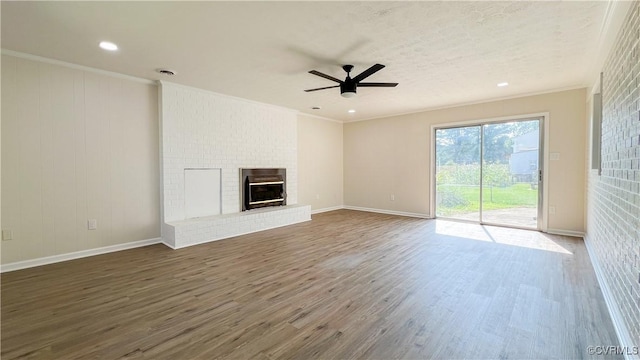 unfurnished living room featuring dark hardwood / wood-style floors, a brick fireplace, ceiling fan, and ornamental molding