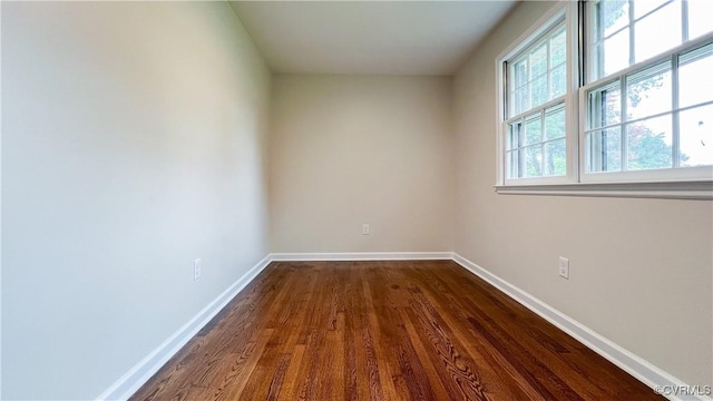 unfurnished room featuring plenty of natural light and dark wood-type flooring