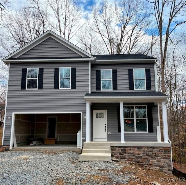 view of front facade with a porch, gravel driveway, and an attached garage