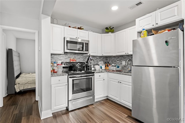 kitchen featuring white cabinets, stainless steel appliances, light stone counters, and dark hardwood / wood-style floors