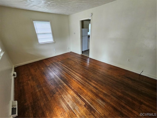 empty room with dark hardwood / wood-style floors and a textured ceiling